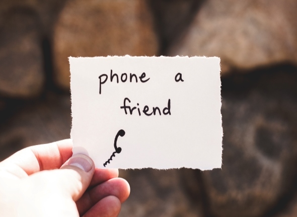 Decorative picture of a hand holding a card saying "phone a friend"