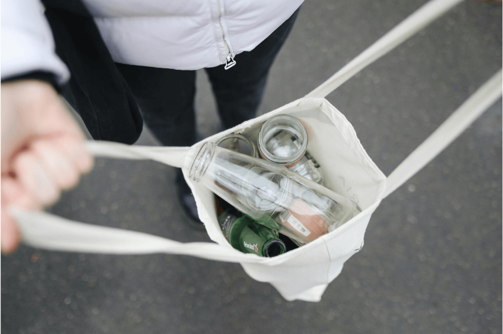 A person holding a bag with glass bottles inside.