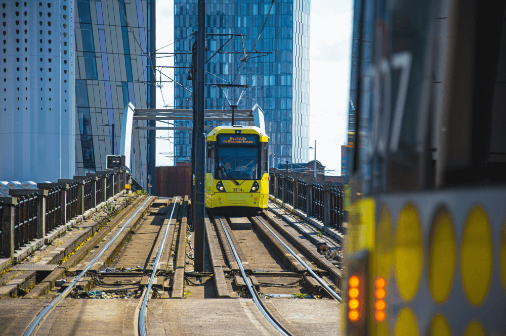A tram in Greater Manchester runs along raised track.