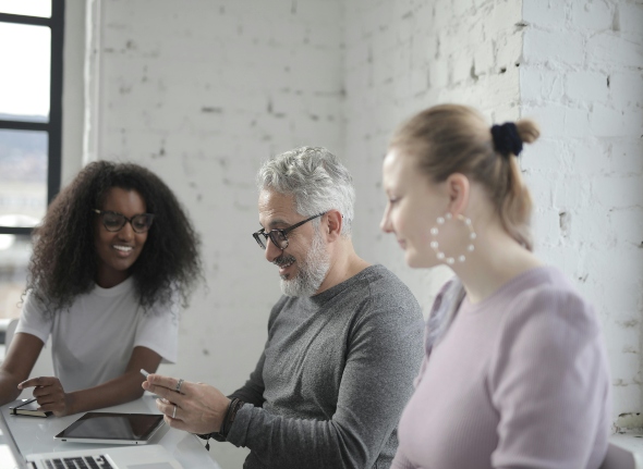 A group of people smiling looking at a computer screen