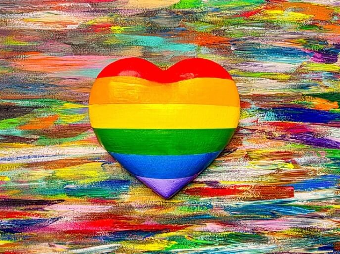 a rainbow coloured heart on a canvas that's been painted on with different colours