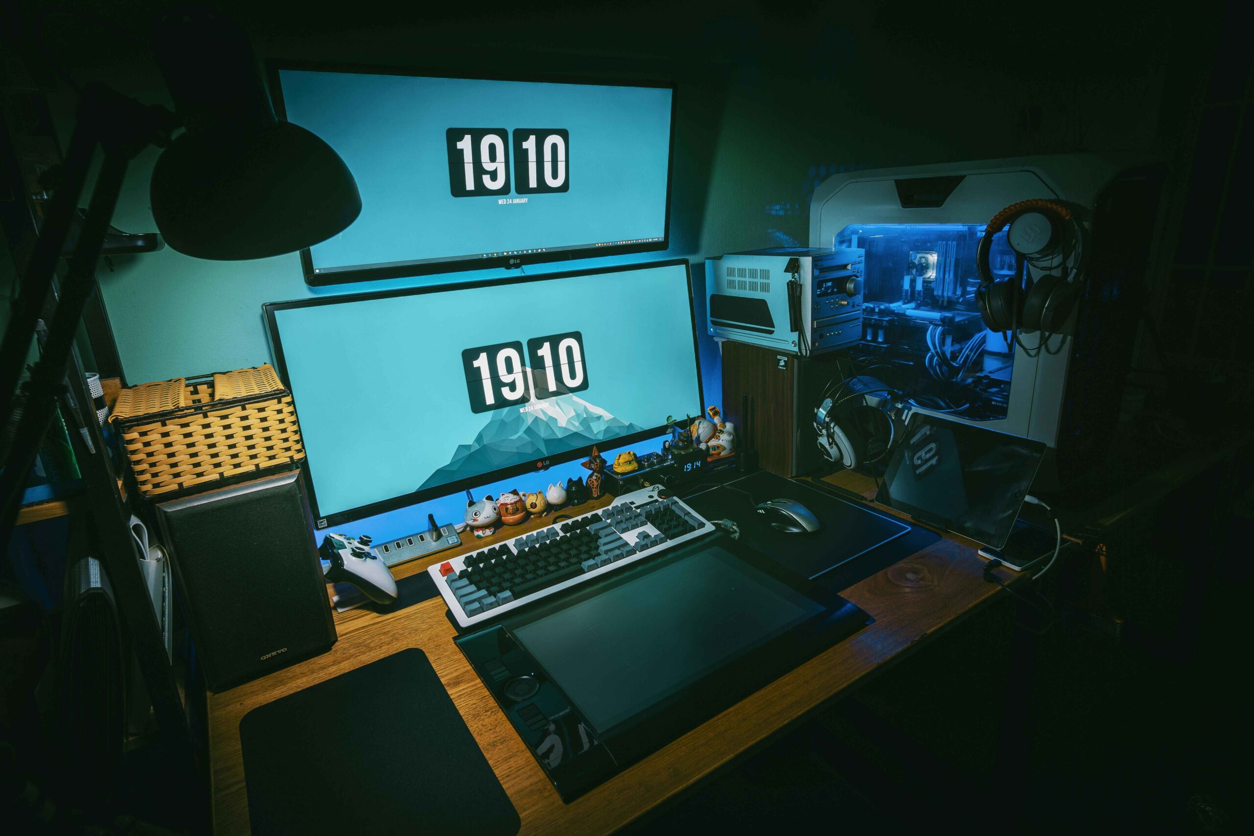 Gaming setup A computer set up in a dark room with multiple screens, headphones and small characters on the desk