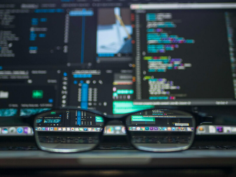 image of glasses with a laptop screen behind displaying code