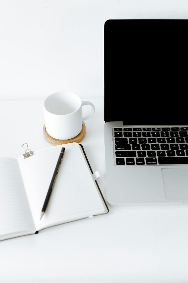 desk which consists of a laptop, book and a mug.