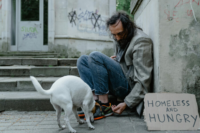 homeless man with dog Man in Blue Denim Jeans Sitting Beside White Short Coat Dog