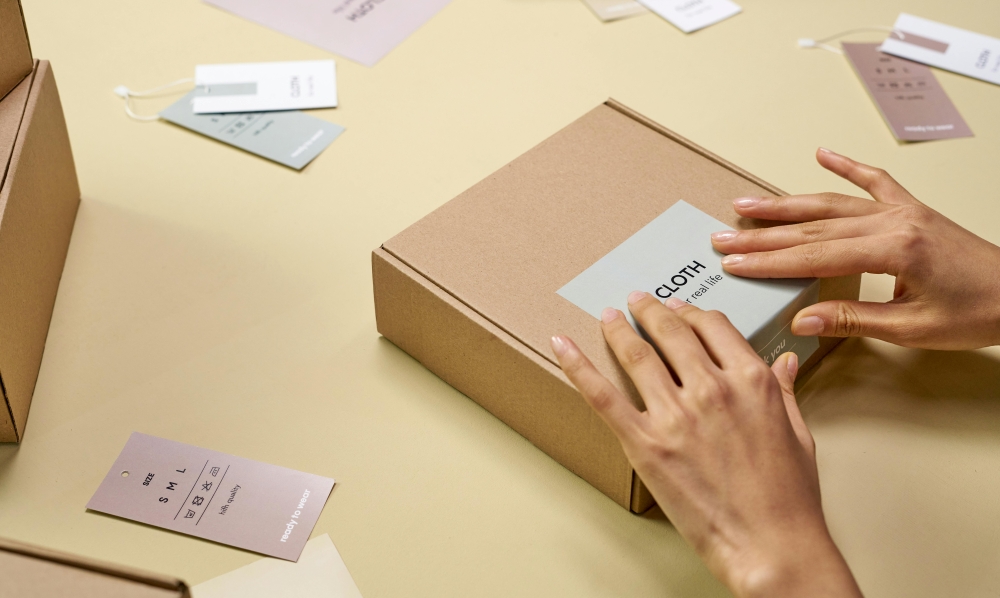A pair of hands are pressing a label onto a packing box